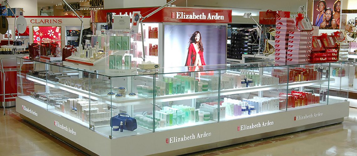 A well-lit Elizabeth Arden cosmetic display in a store, featuring organized skincare and beauty products with a promotional image of a model at the center.